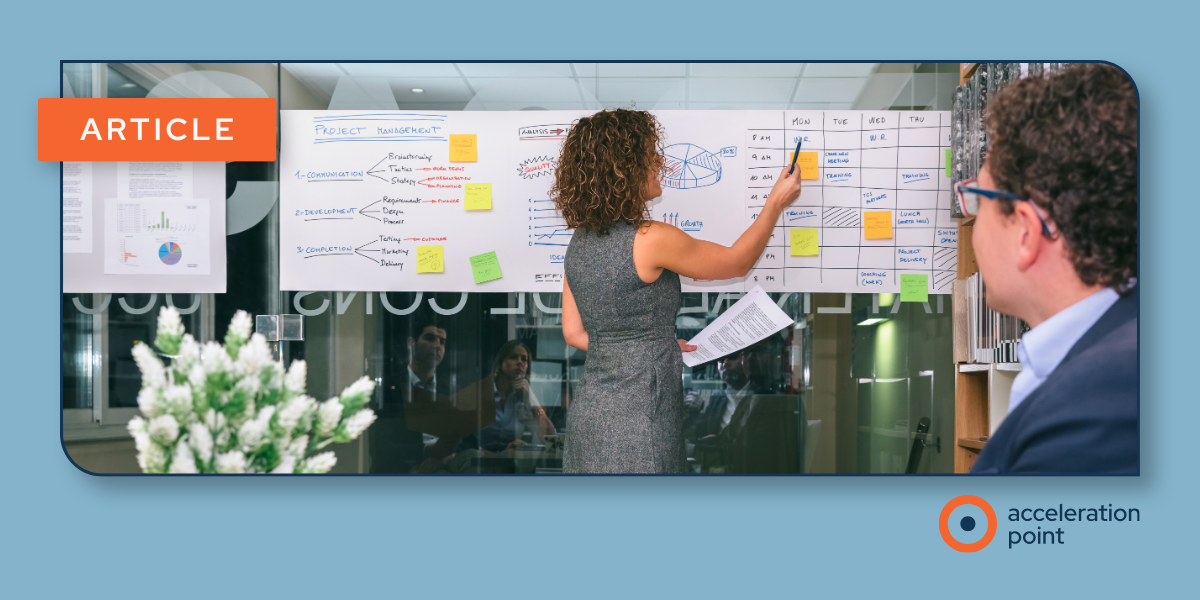 Two colleagues review a project plan and weekly schedule on a whiteboard, reflecting how Medical Affairs teams structure MSL project work.